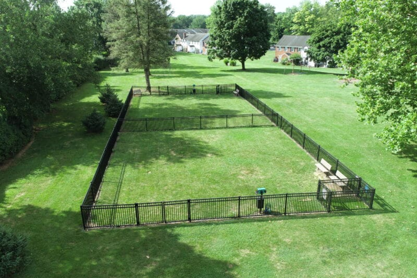 Large fenced in pet park with lush green grass area 