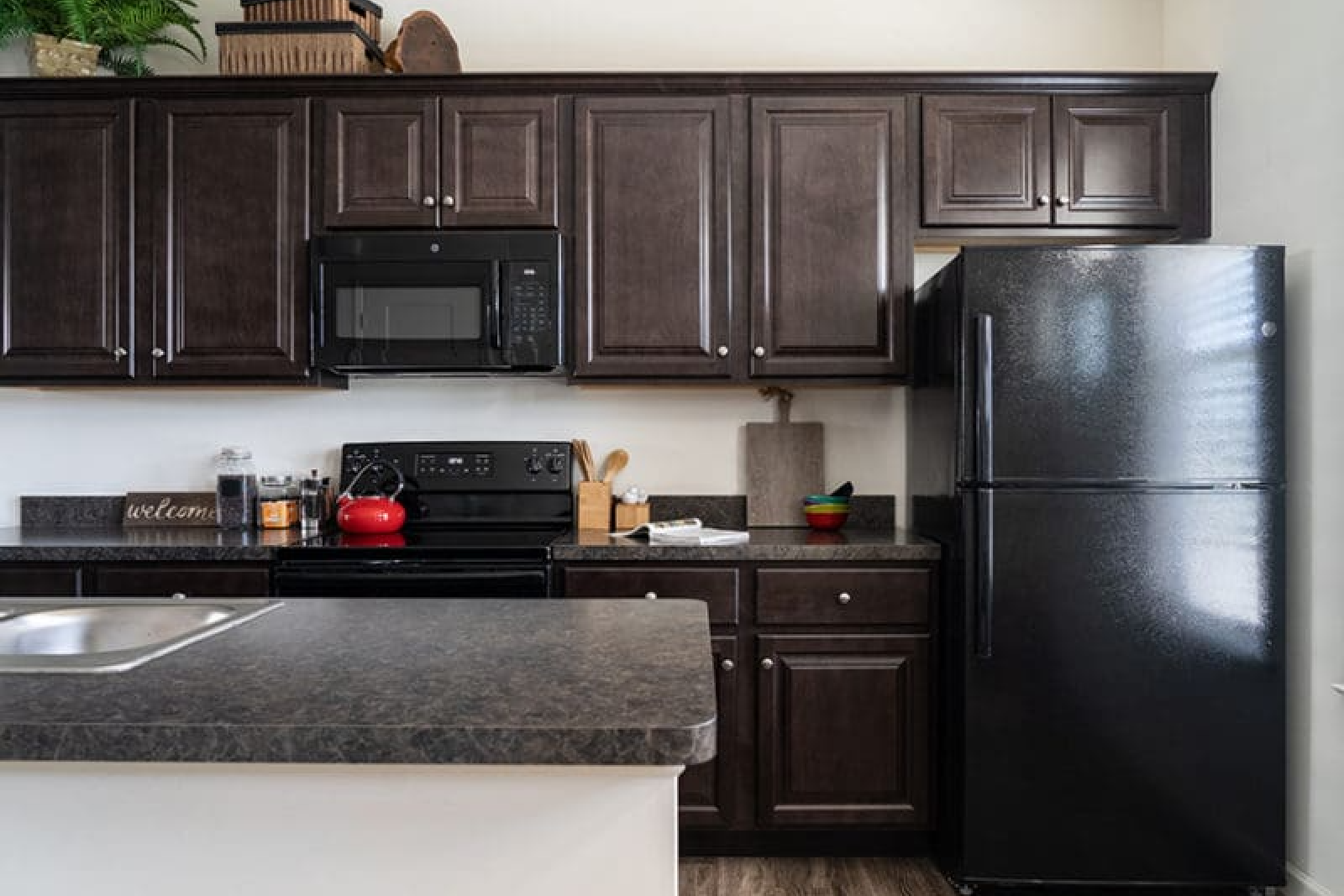 Kitchen area with dark cabinets, spacious counter tops & black appliances