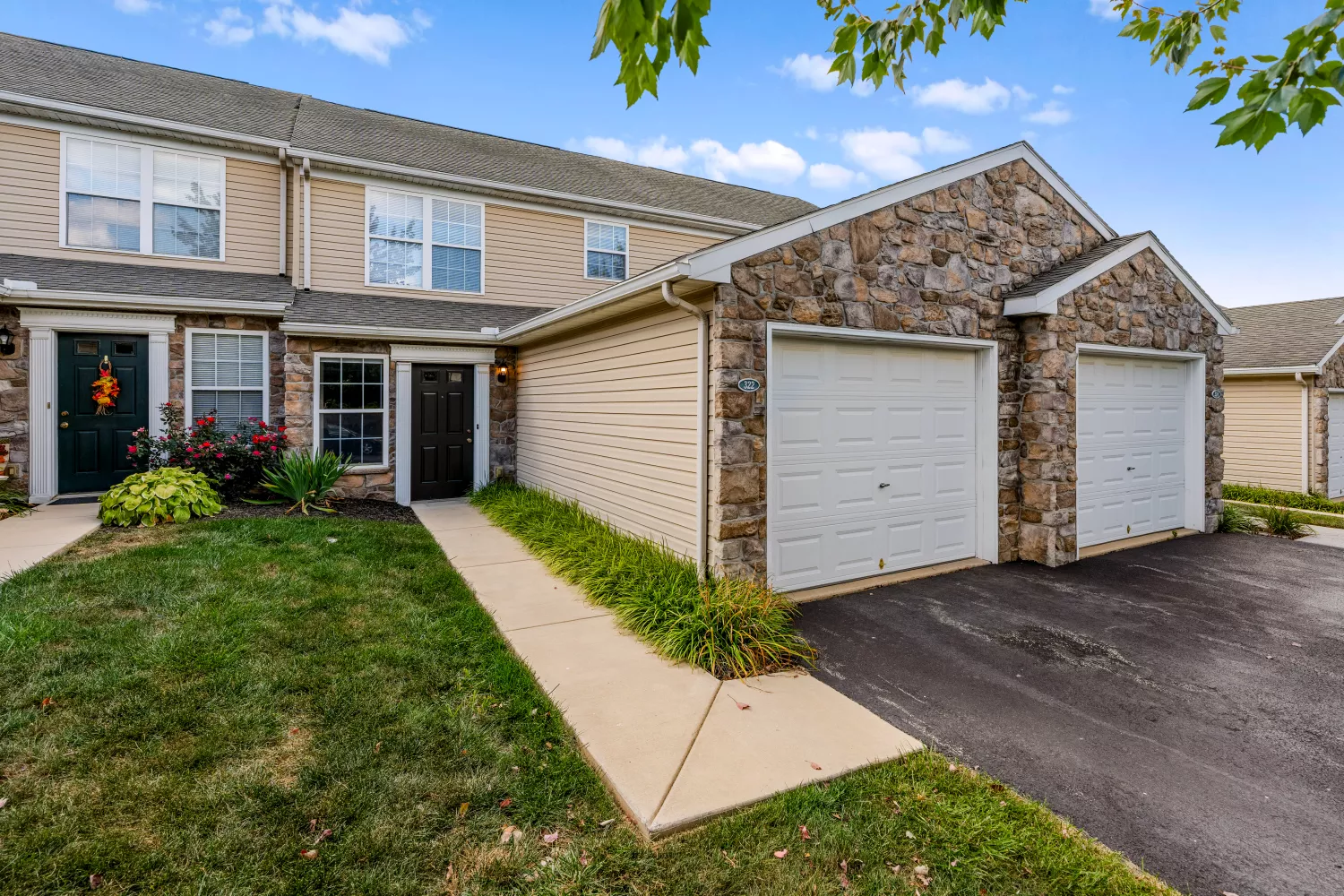 Windsor Commons Townhomes exterior with stone and siding design, private garages, landscaped entry, and welcoming curb appeal