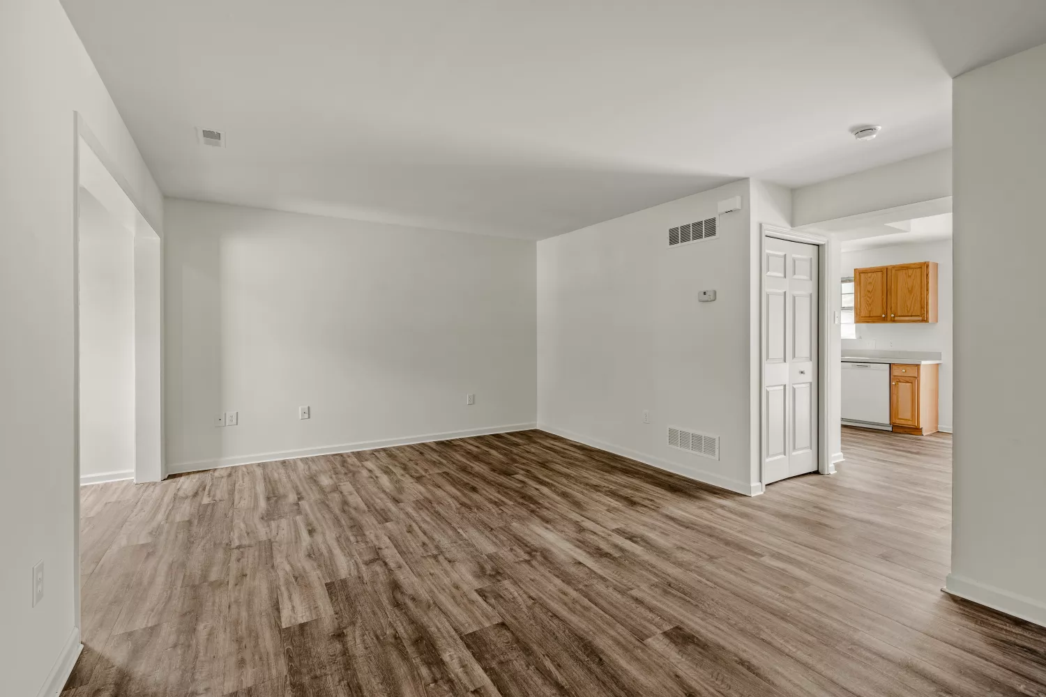 Open-concept living area at Windsor Commons Townhomes with neutral finishes, wood-style flooring, and view into the kitchen