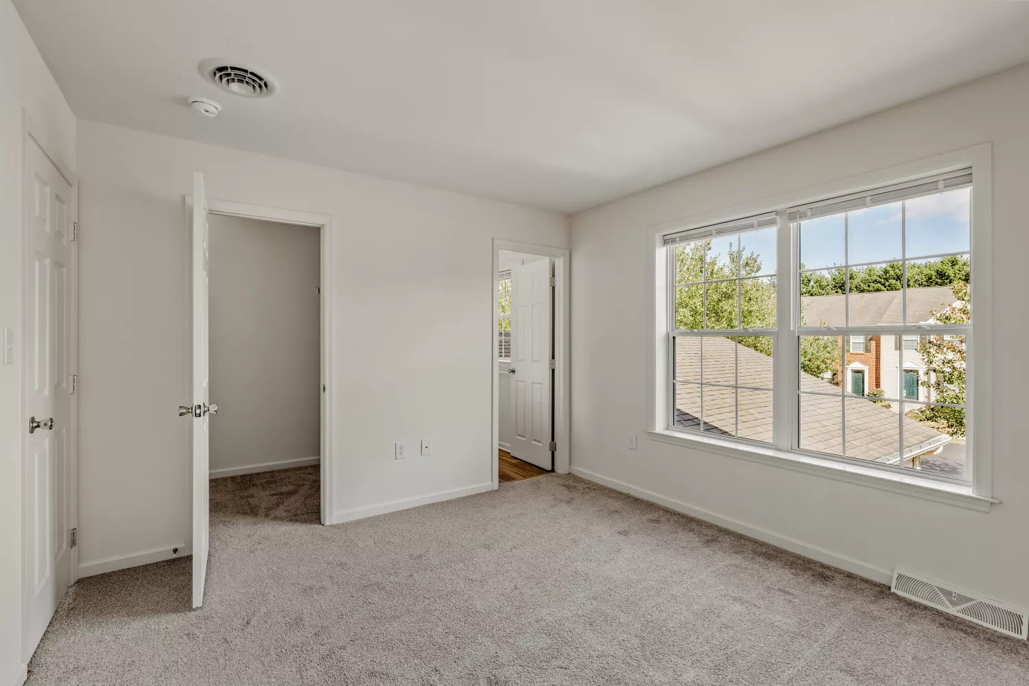 Primary bedroom at Windsor Commons Townhomes featuring plush carpeting, large windows, and spacious walk-in closet