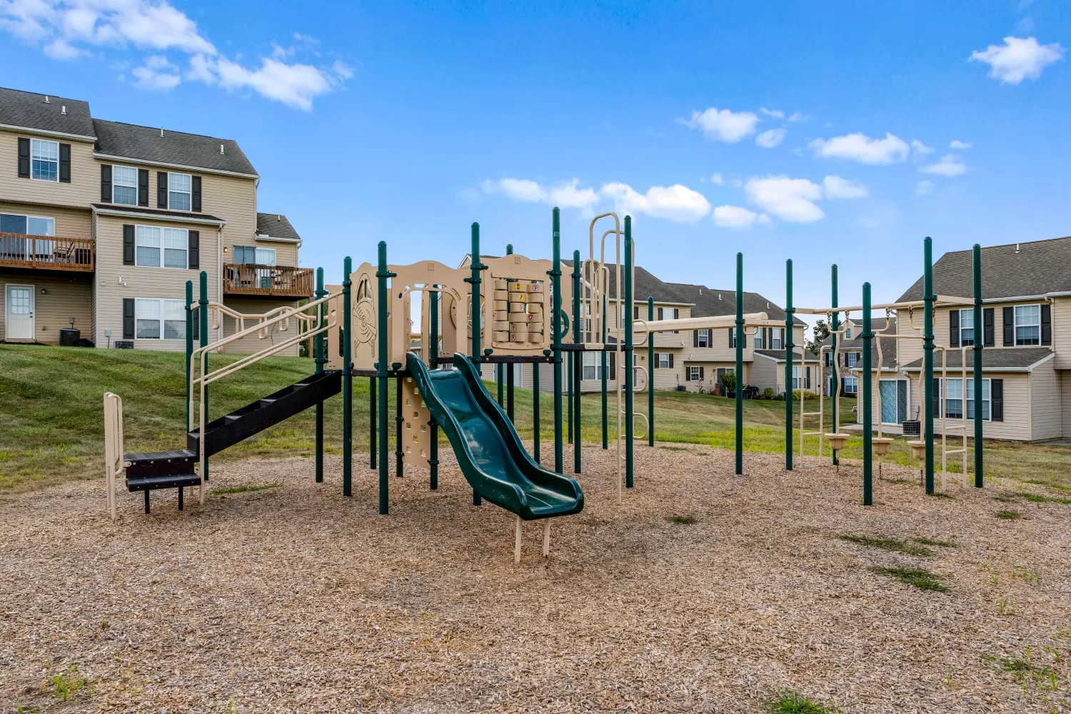 Community playground at Windsor Commons Townhomes featuring slides, climbing equipment, and mulch ground cover.