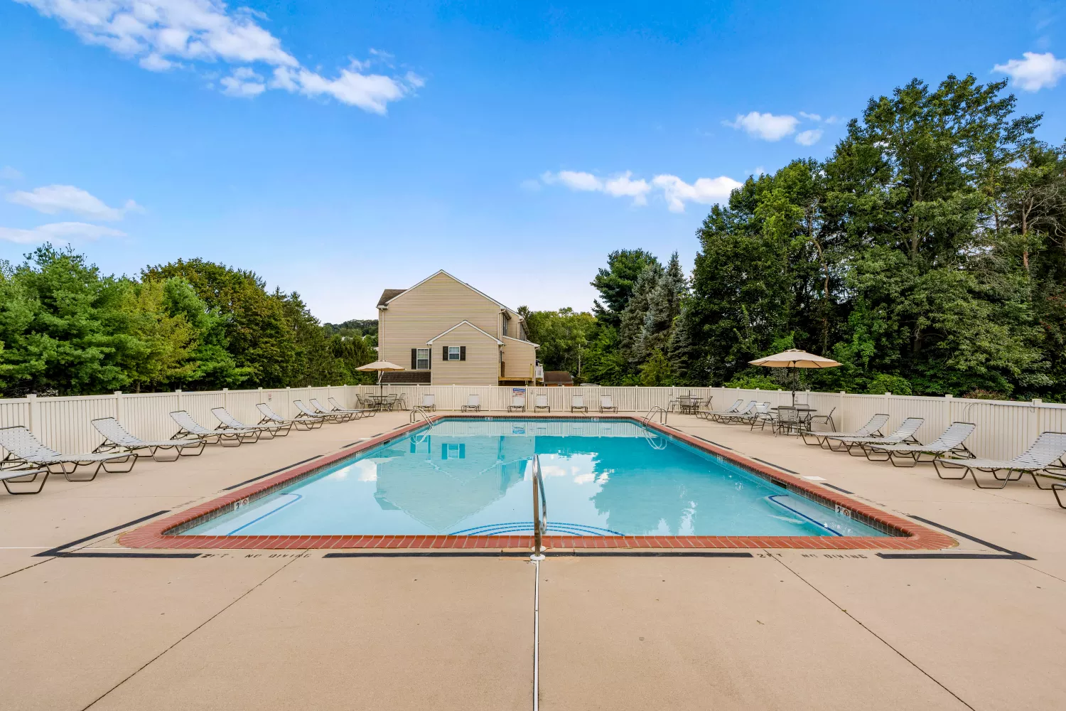 Large community pool at Windsor Commons Townhomes surrounded by lounge seating and shaded tables