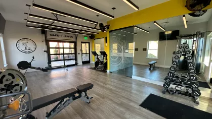 Modern fitness center at The Foundry featuring weight training equipment, cardio machines, mirrored walls, and motivational signage reading “Make It Happen.”