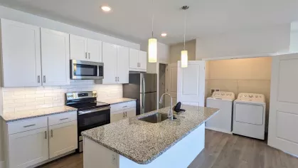 Dedicated laundry space with a full-size washer and dryer set behind double doors, located conveniently near the kitchen.