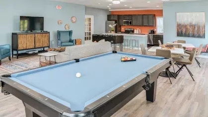 Spacious resident clubhouse featuring a pool table, TV lounge, kitchen area, and modern seating with stylish decor.