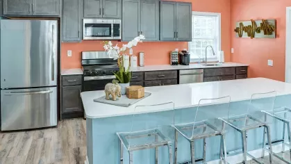 Fully equipped kitchen inside the resident clubhouse with stainless steel appliances, sleek cabinetry, and bar seating.