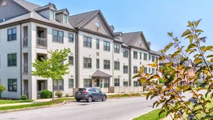 Modern three-story apartment building with private balconies, large windows, and well-maintained landscaping.