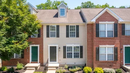 Brick and siding townhome exteriors at Mill Creek Manor with central dormer windows and landscaped entrances