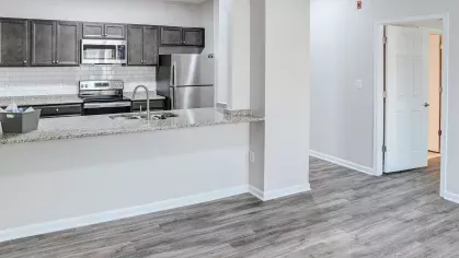 Open-concept kitchen with granite countertops, stainless steel appliances, subway tile backsplash, and dark wood cabinets.