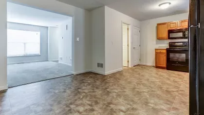 Open-concept kitchen and dining area with vinyl tile flooring and wood cabinetry, seamlessly connected to the living room space at Mill Creek Manor.