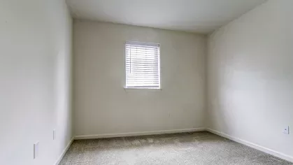 Smaller bedroom or flex space with plush carpeting and single window with blinds, offering a quiet and versatile layout.