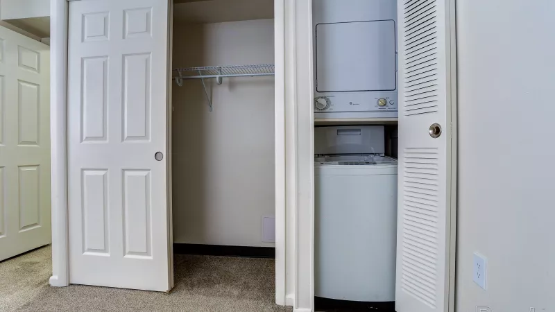 Convenient in-unit stackable washer and dryer setup inside a closet in a renovated Rosedale apartment, alongside extra shelving for storage.