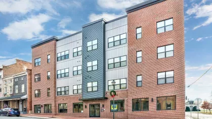 Street view of the modern Riverview Terrace apartment building facade, featuring a contemporary design with large windows, a mix of brick and paneling, and ground-floor retail spaces, inviting urban dwellers.