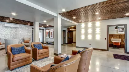 Elegant clubhouse at Stadium Row with comfortable leather seating, modern decor, and concrete flooring, perfect for social gatherings.