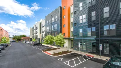 Side view of Stadium Row apartment building and parking lot, highlighting accessible parking spaces and the building's contemporary design with various textured sidings.