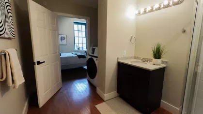Bathroom vanity area with granite countertop and washer-dryer access in a Prince Street Lofts apartment
