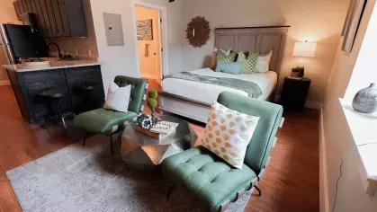 Studio apartment with open layout featuring a cozy bed, kitchen, and seating area at Prince Street Lofts