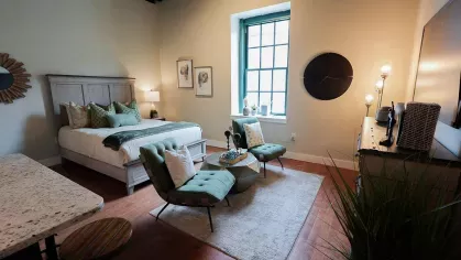 Wide view of studio apartment at Prince Street Lofts with bed, seating area, and central window letting in natural light