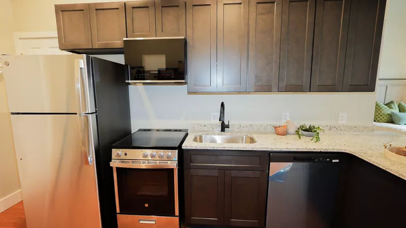 Contemporary kitchen design with upper and lower dark cabinets, granite counters, and modern appliances at Prince Street Lofts