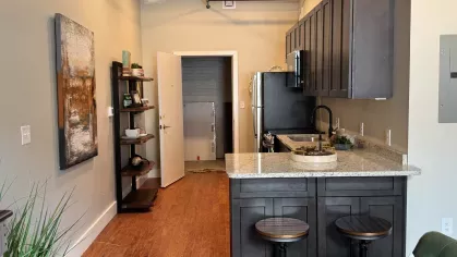 Modern apartment entryway with breakfast bar and open shelving at Prince Street Lofts