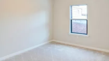 A spacious and bright bedroom at Riverview Terrace, featuring plush carpeting, neutral walls, and a large window with blinds, providing a comfortable and serene space in your new apartment.