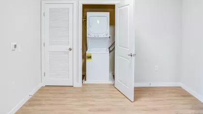 Convenient in-unit stacked white washer and dryer appliances neatly tucked away in a closet at Riverview Terrace apartments, offering effortless laundry access for residents.
