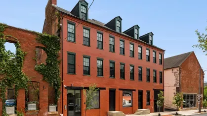 Street-level view of Prince Street Lofts, featuring well-maintained landscaping, vibrant green ivy on adjacent structures, and convenient sidewalk access.