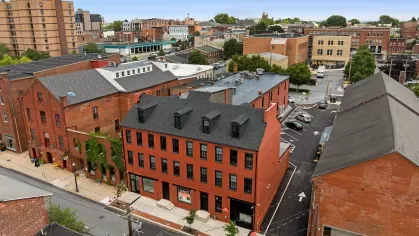 Aerial view of Prince Street Lofts in Downtown Lancaster, PA, showcasing the red-brick façade, rooftop dormers, and surrounding historic architecture.