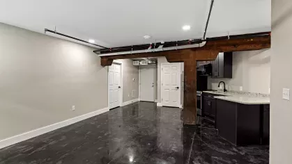 View of the kitchen from the entryway, revealing the mix of contemporary and historic elements including original timber support columns.