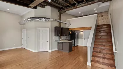 Open-concept loft with vaulted ceilings and industrial ductwork, showcasing a blend of historic charm and modern upgrades.