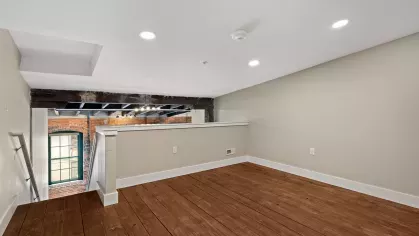 Lofted upper-level area overlooking the living room, ideal for a cozy bedroom or flexible workspace with wood flooring and recessed lighting.