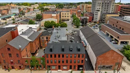 Drone shot of Prince Street Lofts and neighboring buildings, emphasizing the urban setting, on-site parking, and central downtown location.