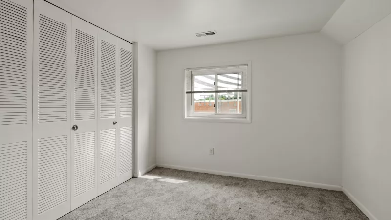 Spacious bedroom at Rosedale Apartments with plush carpet, large closet doors, and natural light from window