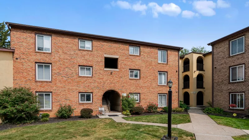 Brick and stucco apartment buildings at Rosedale Apartments with landscaped pathways and resident entrances