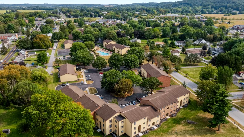Overhead aerial view of Rosedale Apartments showcasing multiple buildings, outdoor pool, landscaped green space, and surrounding neighborhood