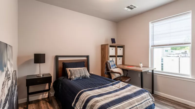 Cozy guest bedroom or office setup at Wyndham Pointe with twin bed, desk, and large window providing ample daylight.