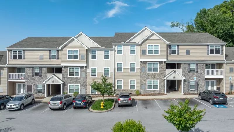 Wide view of Wyndham Pointe apartment community featuring multiple connected buildings with balconies and parking spaces in front.