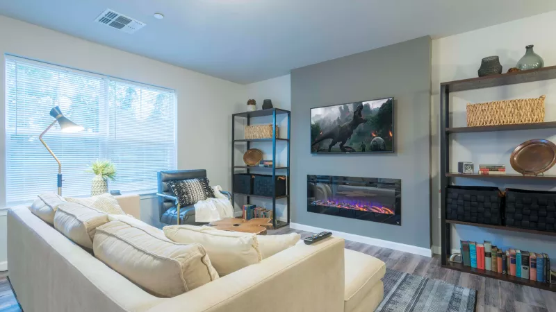 Wyndham Pointe living area with sectional sofa, modern fireplace, mounted TV, and shelving for décor and books.