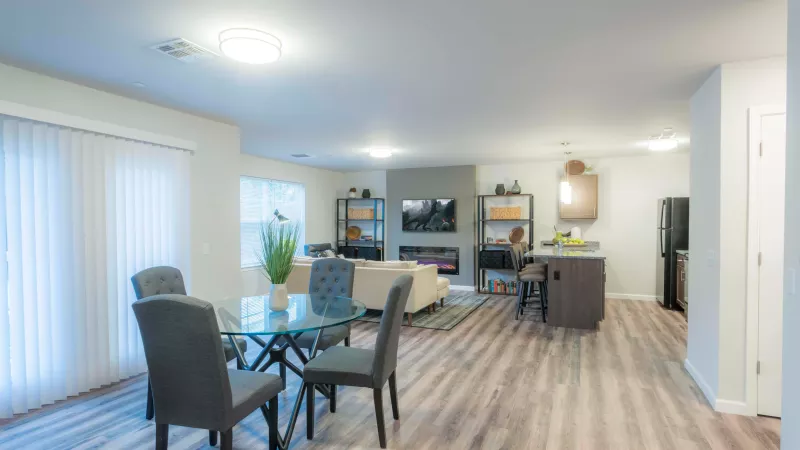 Open-concept kitchen and dining space at Wyndham Pointe Apartments with glass dining table, pendant lighting, and plank flooring.