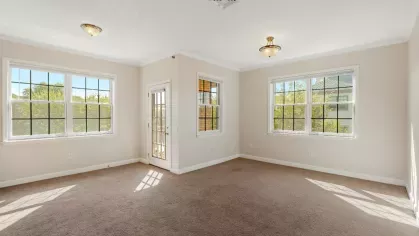 Living and dining area with large windows, neutral walls, and access door to the balcony.
