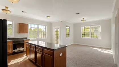 Open kitchen and living area with center island, natural light from multiple windows, and spacious layout.