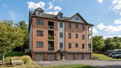 Four-story brick apartment building with attached garages on the ground level and private balconies above.