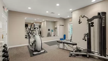 Fitness center room with elliptical machine, weight bench, free weights, and wall mirror.
