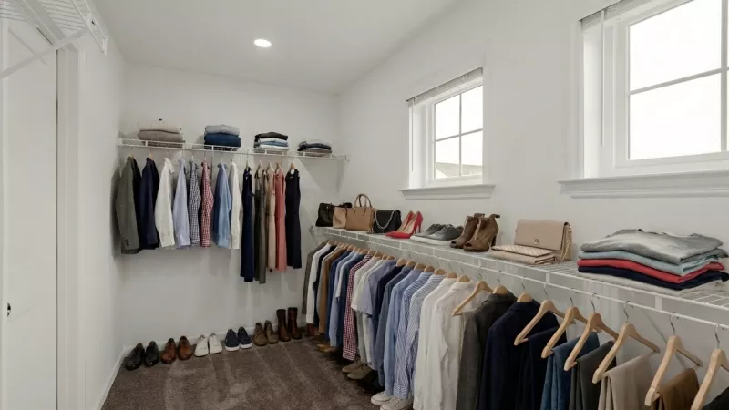 A large walk-in closet with built-in wire shelving and hanging rods. Two windows provide natural light to the organized storage space.