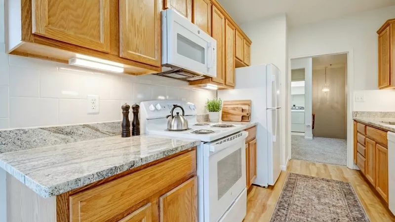 A view of the kitchen workspace showing the white electric range, microwave, and dishwasher, leading toward an adjacent laundry area.