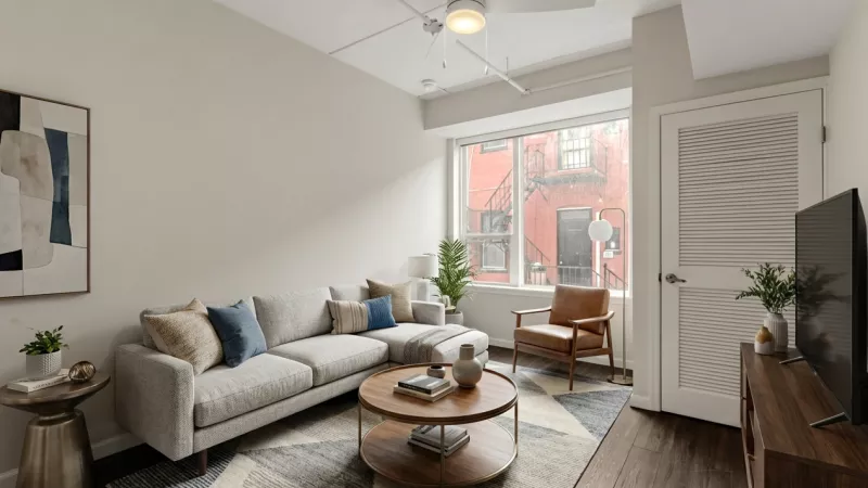 Modern living room with a gray sectional sofa, wooden coffee table, and a brown leather armchair.