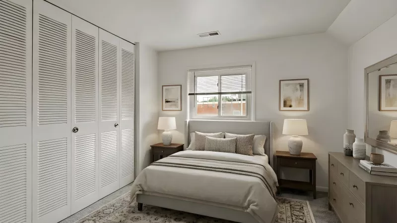 A bright bedroom with a bed, two nightstands, a dresser with a mirror, and white closet doors with a wavy pattern.