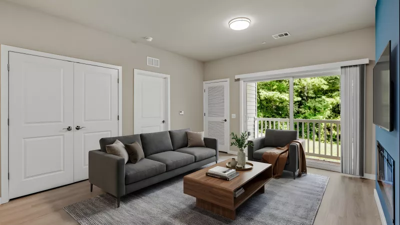 Bright living room with grey sofa, wooden coffee table, and armchair. Blue accent wall with TV, fireplace. Balcony view.