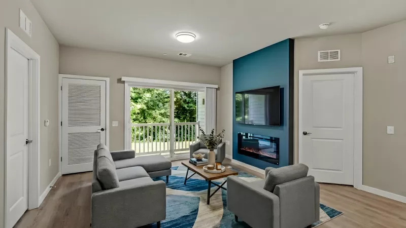 Modern living room with gray furniture, blue accent wall, mounted TV, electric fireplace, and balcony access.